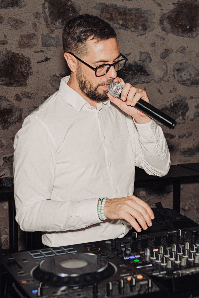 dj de mariage tenant un micro en main et mixant sur sa platine lors d'un mariage à clermont-l'hérault près de Montpellier