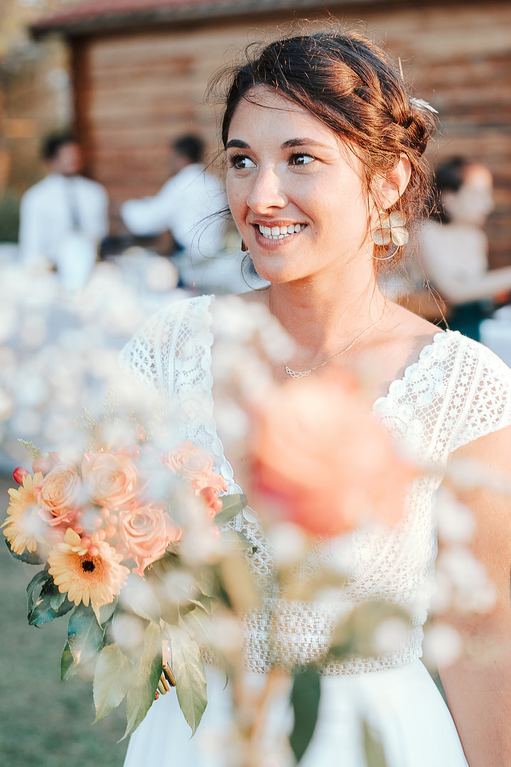 jeune mariée toute sourire avec son bouquet dans les mains portant une robe de mariée cymbeline